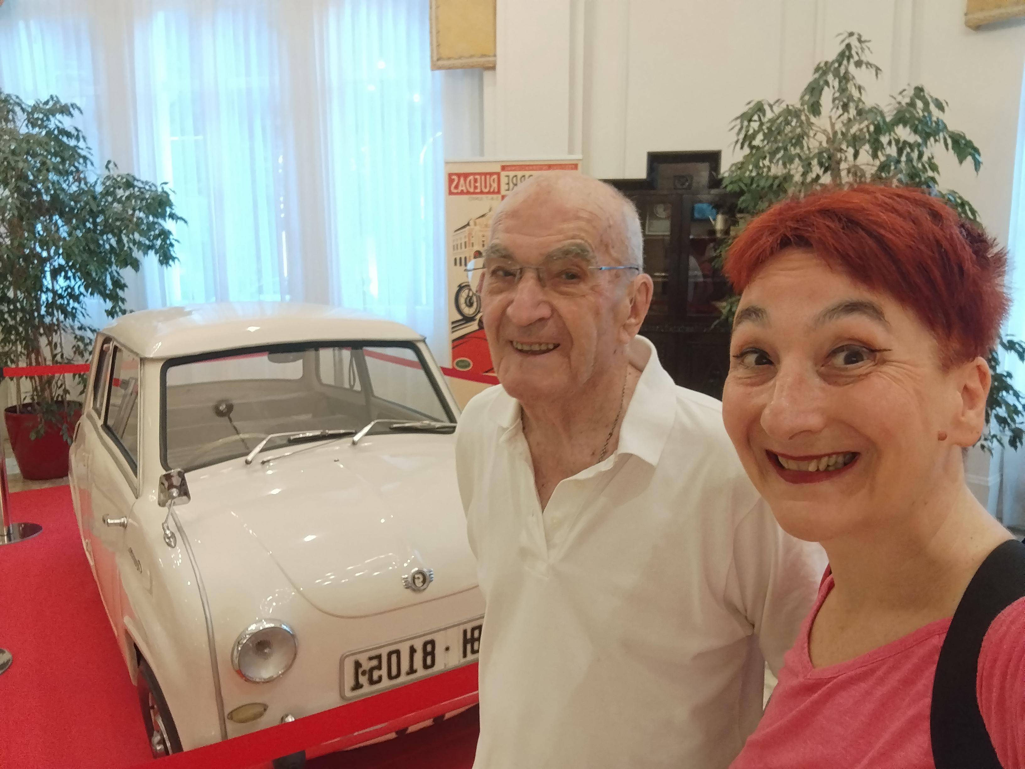 Aita eta biok irribarretsu Goggomovil zuri baten aurrean. Aitoa txikitxoa da eta alfonbra gorri baten gainean dago. Aitak niki zuria darama eta nik kamiseta arrosa